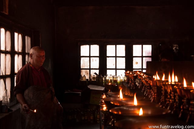 A monk lights candles before evening sets in.