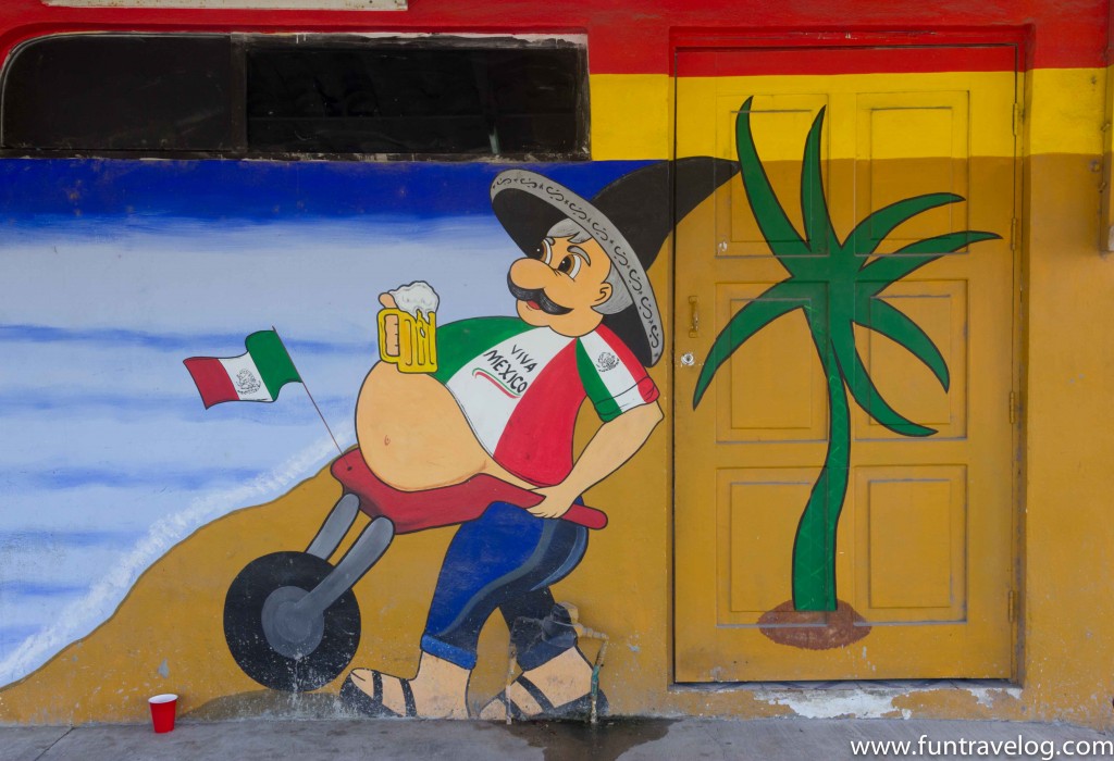 Visiting Tulum? Don't miss the graffiti on the streets. Photo of a painted man with a wheelbarrow, holding beer