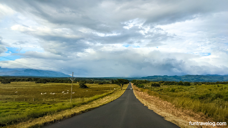 A panorama of a paved road in Costa Rica, surrounded by greenery