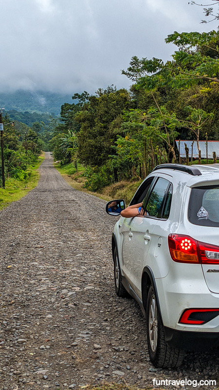 While renting a car in Costa Rica, be aware about unpaved roads. Photo of a car on a graveled road in rural Costa Rica.